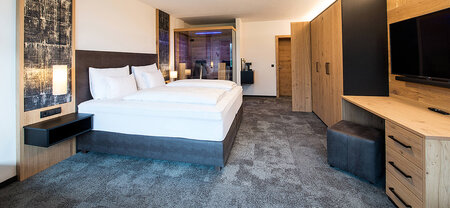 Modern double room with box spring bed, large wardrobe, desk and glass sauna cabin