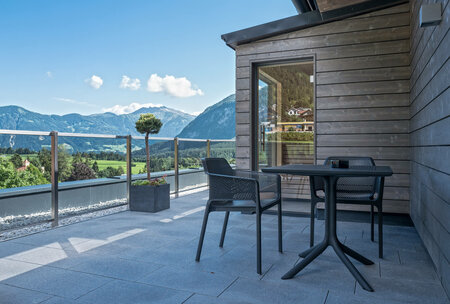Moderne Terrasse mit Tisch, zwei Stühlen und Panoramablick auf das Tiroler Alpenpanorama