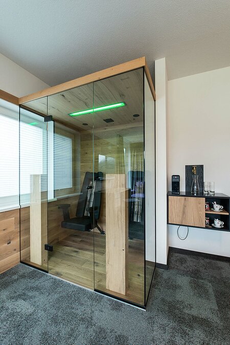 Infrared cabin in hotel room with glass doors, wooden panels and modern coffee machine