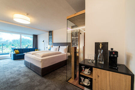 Comfortable room with large bed, sofa, infrared cabin and view of mountains and village