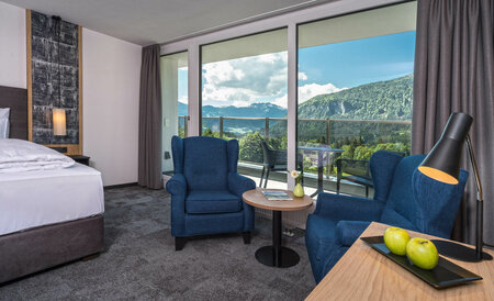 Bright hotel room with two blue armchairs, panorama window and stunning mountain view