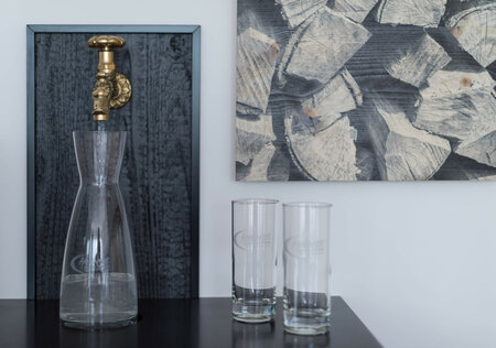 Designer water station with glass carafe, drinking glasses and stylish wall-mounted tap