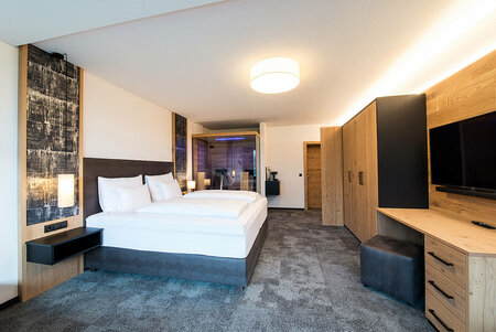 Modern double room with box spring bed, large wardrobe, desk and glass sauna cabin