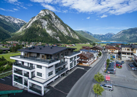 Modern hotel building with mountain views in summer, surrounded by traditional houses